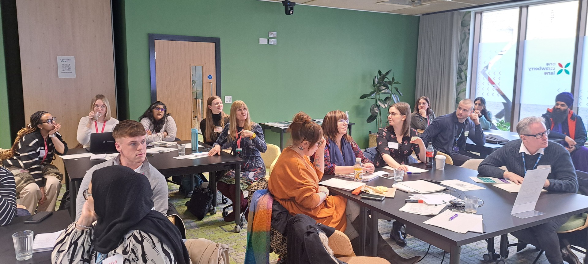 People sat around tables listening to a presentation